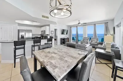 a kitchen and living room with a table and chairs at Calypso 1209W Corner 3BR 3BA 2 sets of beach service in Panama City Beach