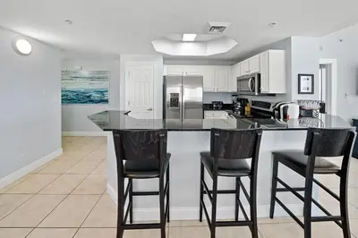a kitchen with a large island with bar stools at Calypso 1209W Corner 3BR 3BA 2 sets of beach service in Panama City Beach