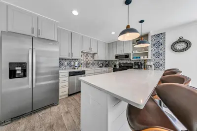 a kitchen with white cabinets and stainless steel appliances at Tiki Palms Paradise by Emerald Coast Retreats in Panama City Beach