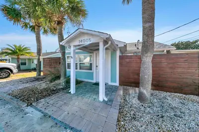 a house with a phone booth in front of a fence at Tiki Palms Paradise by Emerald Coast Retreats in Panama City Beach