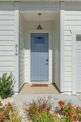 a blue door on a white house with flowers at Laid-Back - Private Pool, 4 Min Walk to Beach, Close to 30A, FREE Daily Activities in Panama City