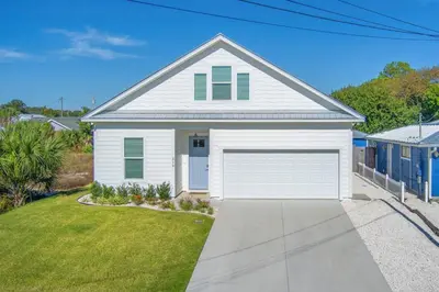 a white house with a garage at Laid-Back - Private Pool, 4 Min Walk to Beach, Close to 30A, FREE Daily Activities in Panama City
