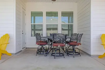a patio with a table and chairs on a porch at Laid-Back - Private Pool, 4 Min Walk to Beach, Close to 30A, FREE Daily Activities in Panama City