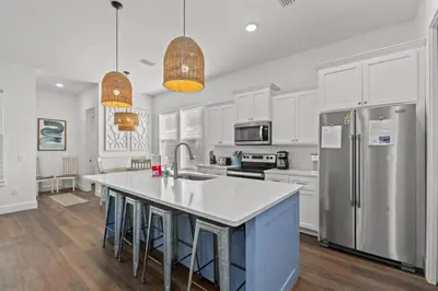a kitchen with white cabinets and a kitchen island with stools at Laid-Back - Private Pool, 4 Min Walk to Beach, Close to 30A, FREE Daily Activities in Panama City