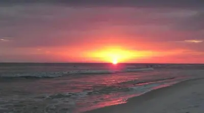 a sunset on a beach with the ocean at Grand Panama 902 in Panama City Beach
