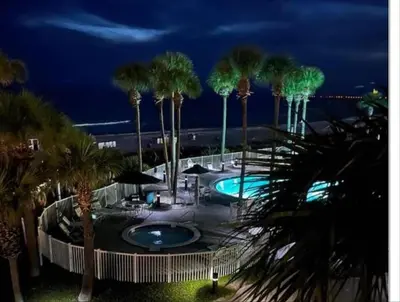a view of a pool with palm trees at night at Grand Panama 902 in Panama City Beach