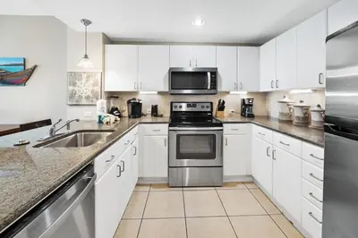 a kitchen with white cabinets and stainless steel appliances at Grand Panama 904 in Panama City Beach