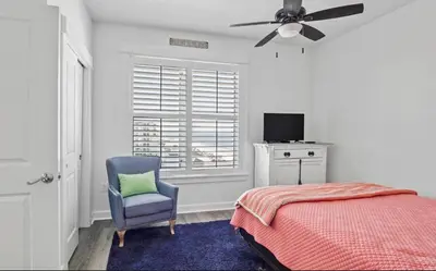 a bedroom with a bed and a chair and a ceiling fan at Grand Panama 909 in Panama City Beach