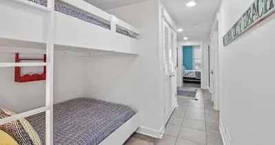 a room with white bunk beds and a hallway at Grand Panama 909 in Panama City Beach