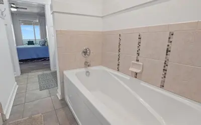 a white bath tub in a bathroom with a table at Grand Panama 909 in Panama City Beach