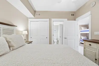 a bedroom with a large white bed and a bathroom at Grand Panama 1003 in Panama City Beach