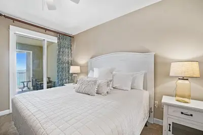 a bedroom with a white bed and a balcony at Grand Panama 1003 in Panama City Beach