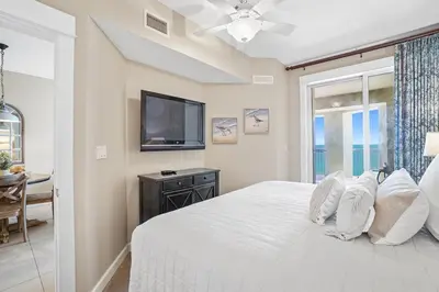 a bedroom with a white bed and a tv at Grand Panama 1003 in Panama City Beach