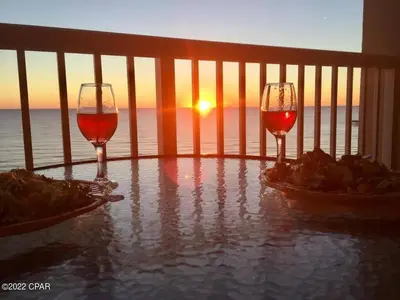 two glasses of wine on a balcony with the sunset at Grand Panama 1204 in Panama City Beach