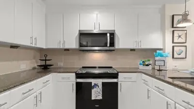 a kitchen with white cabinets and a black stove at Grand Panama 1307 in Panama City Beach