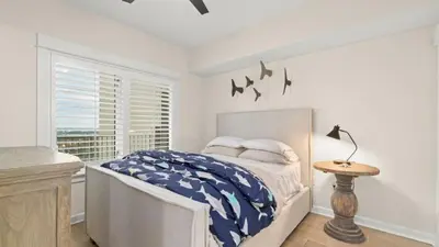 a white bedroom with a bed and a window at Grand Panama 1307 in Panama City Beach