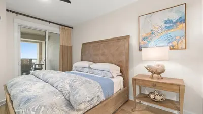 a bedroom with a bed and a table with a lamp at Grand Panama 1307 in Panama City Beach