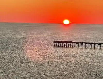 a sunset over the ocean with a pier in the water at Grand Panama 1405 in Panama City Beach