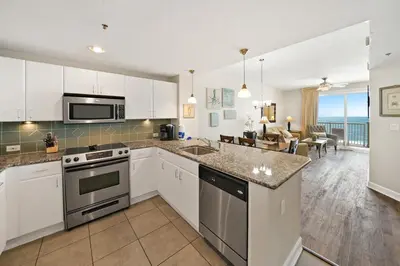 a kitchen with white cabinets and a view of the ocean at Grand Panama 1405 in Panama City Beach