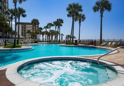 a large swimming pool with blue water and palm trees at Grand Panama 1405 in Panama City Beach
