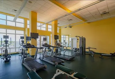a gym with several tread machines in a room with windows at Grand Panama 1405 in Panama City Beach