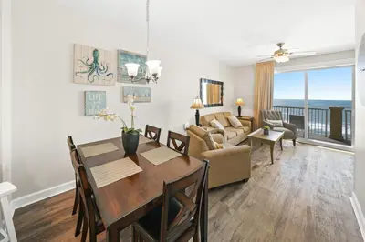 a dining room and living room with a table and chairs at Grand Panama 1405 in Panama City Beach