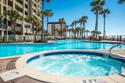 a swimming pool with palm trees in a resort at Grand Panama 1406 in Panama City Beach