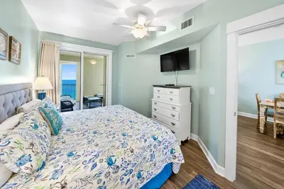 a bedroom with a bed and a dresser with a tv at Grand Panama 1406 in Panama City Beach