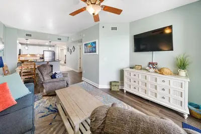 a living room with a ceiling fan and a tv at Grand Panama 1406 in Panama City Beach