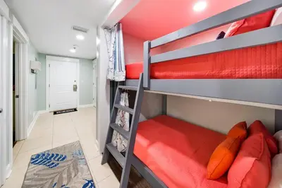 a bedroom with two bunk beds with red sheets at Grand Panama 1406 in Panama City Beach