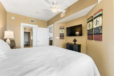 a bedroom with a white bed and a ceiling fan at Grand Panama 1408 in Panama City Beach