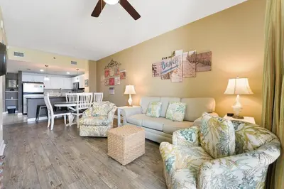 a living room with a couch and chairs and a kitchen at Grand Panama 1408 in Panama City Beach