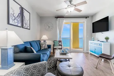 a living room with a blue couch and a table at Grand Panama 1508 in Panama City Beach
