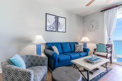 a living room with a blue couch and a table at Grand Panama 1508 in Panama City Beach