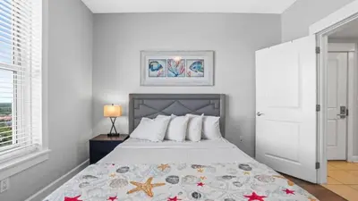 a white bedroom with a bed with a starfish blanket at Grand Panama 1801 in Panama City Beach