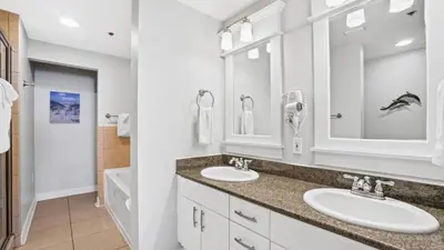 a bathroom with two sinks and two mirrors at Grand Panama 1801 in Panama City Beach
