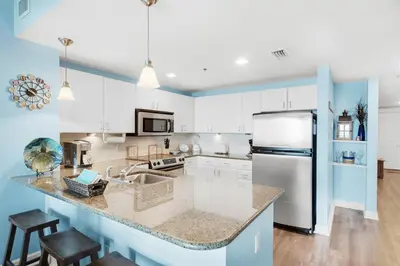 a kitchen with white cabinets and a refrigerator at Grand Panama 1806 in Panama City Beach