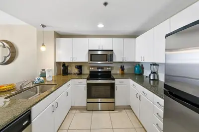 a kitchen with white cabinets and stainless steel appliances at Grand Panama 2004 in Panama City Beach