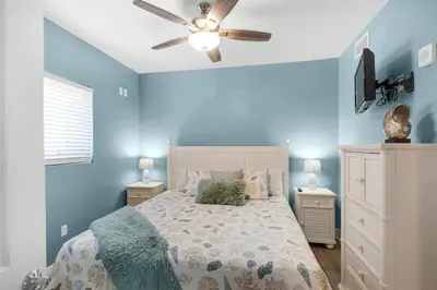a bedroom with a bed with blue walls and a ceiling fan at Sterling Breeze 401 in Panama City Beach