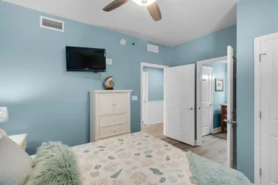 a bedroom with blue walls and a bed and a flat screen tv at Sterling Breeze 401 in Panama City Beach