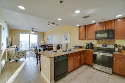 a kitchen with wooden cabinets and a living room at Sterling Breeze 406 in Panama City Beach