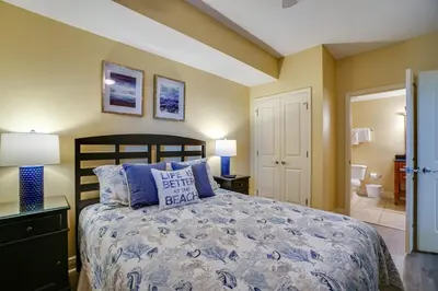 a bedroom with a large bed with blue pillows at Sterling Breeze 406 in Panama City Beach