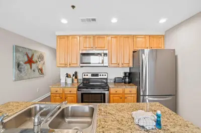 a kitchen with stainless steel appliances and wooden cabinets at Splash 903W in Panama City Beach