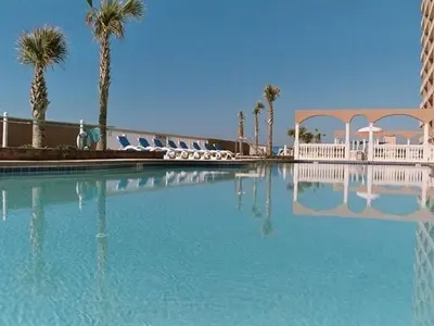 a large swimming pool with palm trees and a building at Sunrise Beach 801 in Panama City Beach