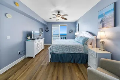 a bedroom with blue walls and a bed and a couch at Sunrise Beach 801 in Panama City Beach