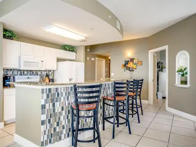 a kitchen with a bar with stools at Sunrise 2401 in Panama City Beach