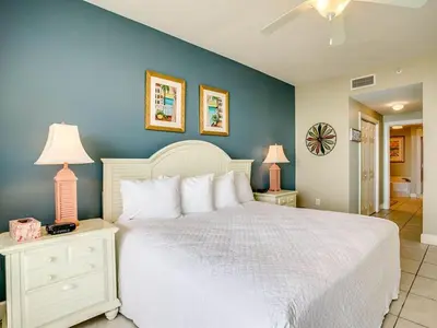 a bedroom with a white bed and a blue wall at Sunrise 2401 in Panama City Beach
