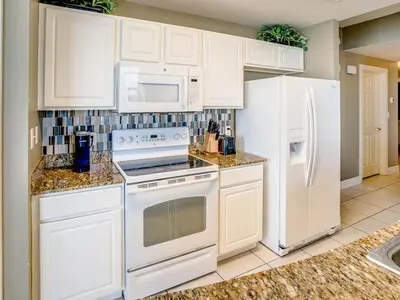 a kitchen with white appliances and white cabinets at Sunrise 2401 in Panama City Beach