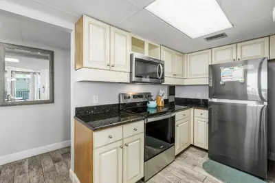a kitchen with white cabinets and a stainless steel refrigerator at Aquavista E406 in Panama City Beach