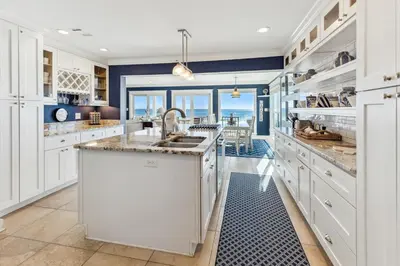 a kitchen with white cabinets and a large island at Spring Break Promo! Gulf Front Home with Private Beach Access with Bikes! in Inlet Beach